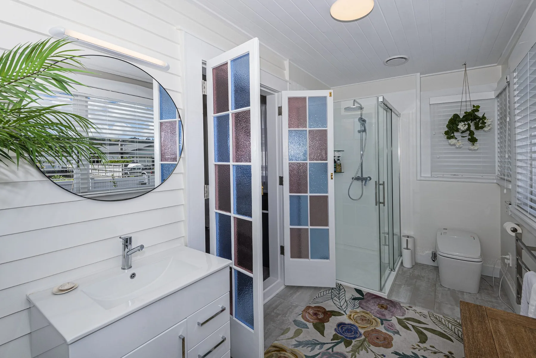 Light-coloured bathroom with timber flooring and a glazed shower