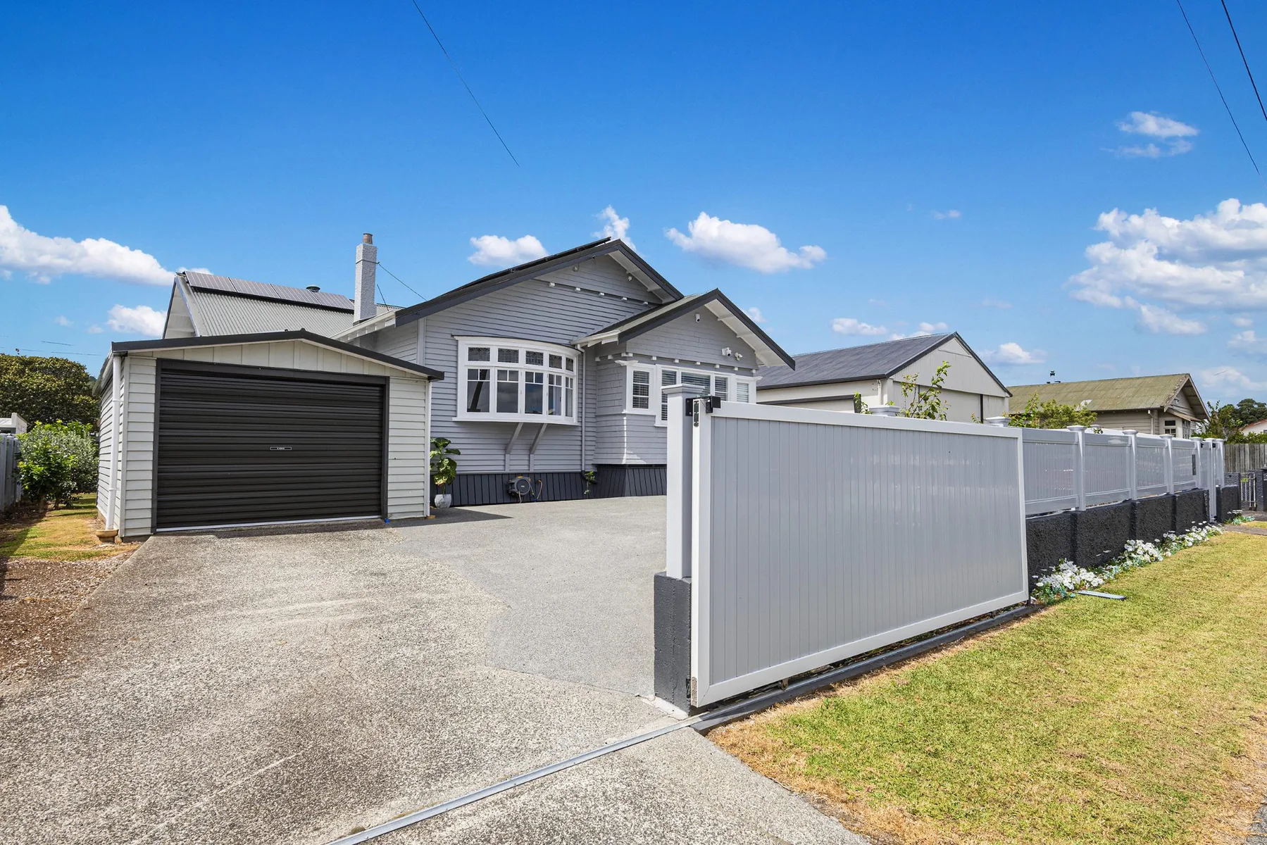 Later front view of the Kensington bungalow with a dark garage door and white boundary fence