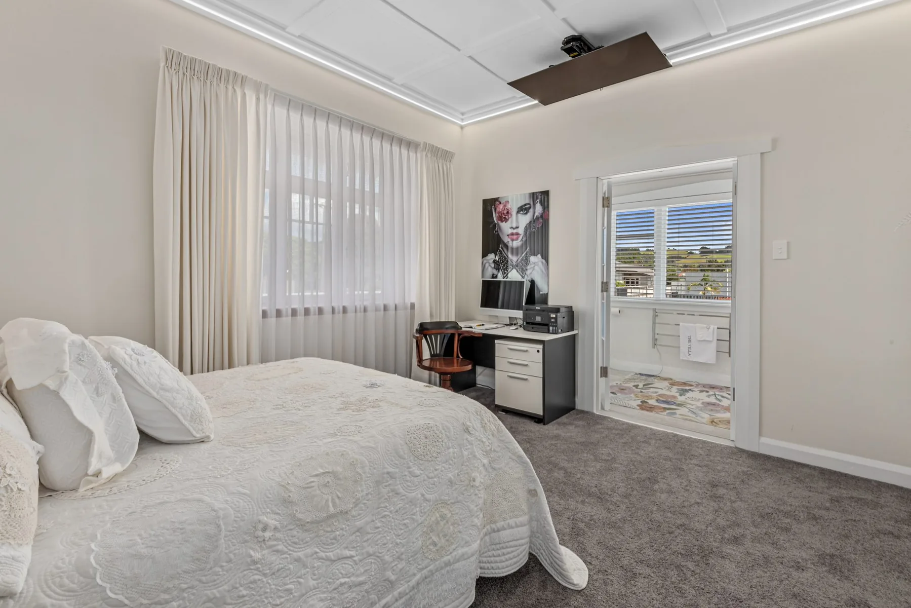 Finished master bedroom with light walls, grey carpet and full-height curtains