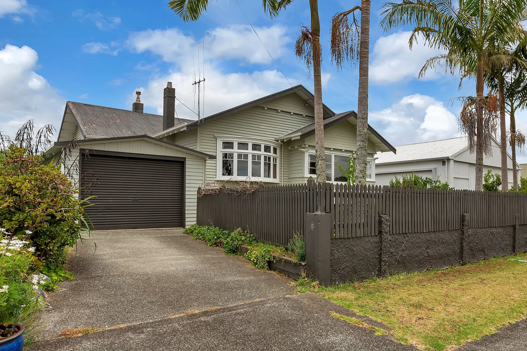 Earlier front view of the Kensington bungalow with a dark garage and dark picket fence