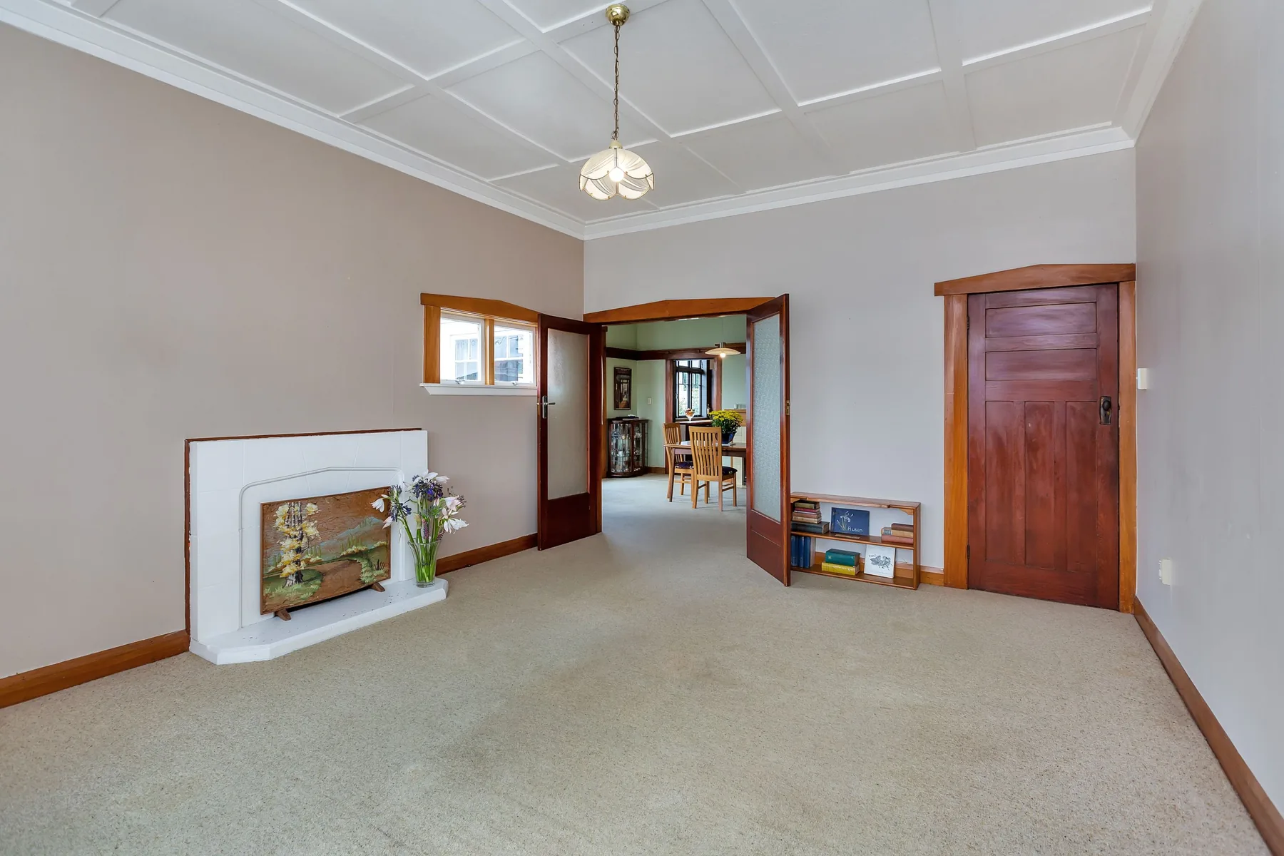 Earlier lounge with timber doors, fireplace, patterned ceiling and pale carpet