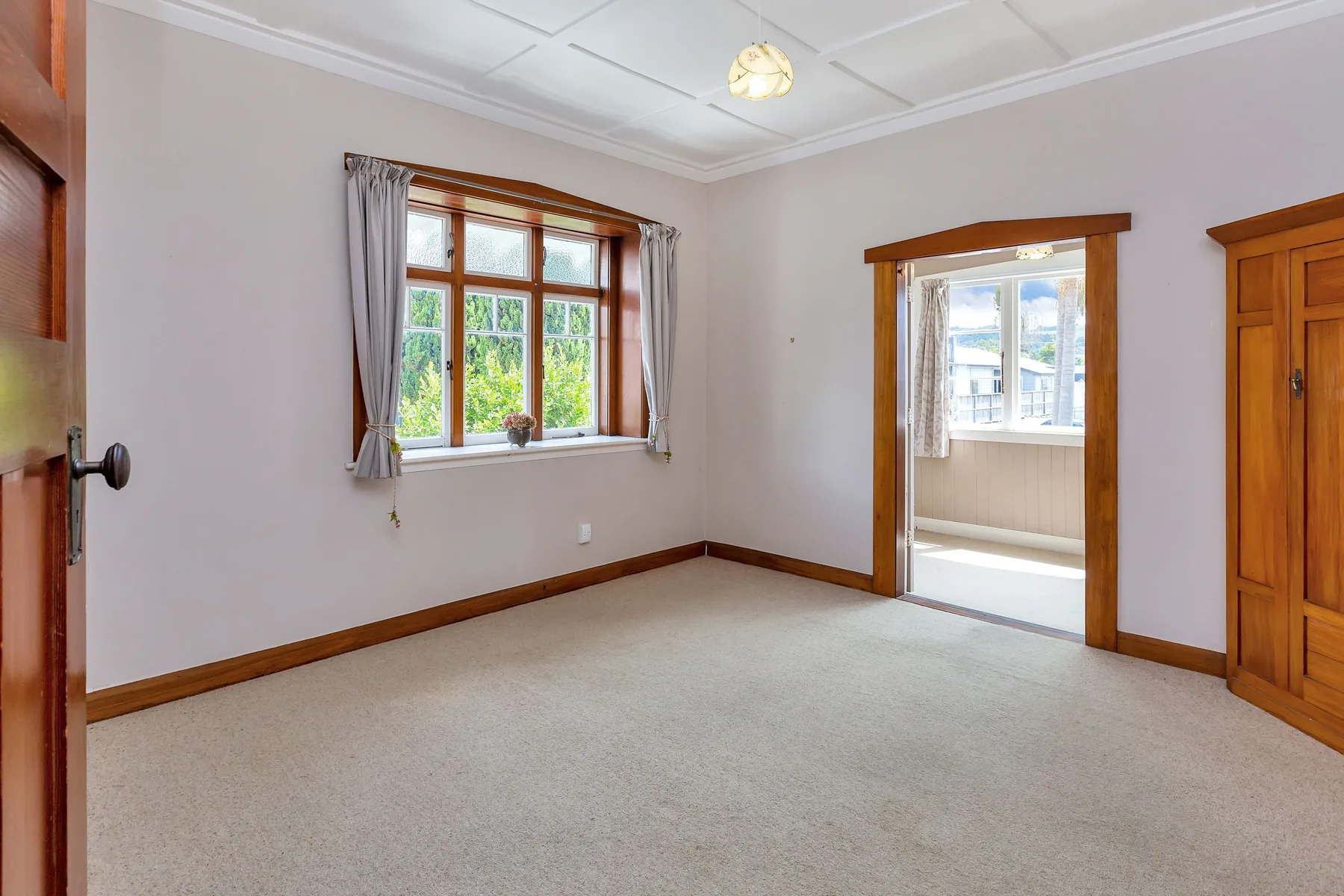 Earlier master bedroom with timber window trim and pale carpet