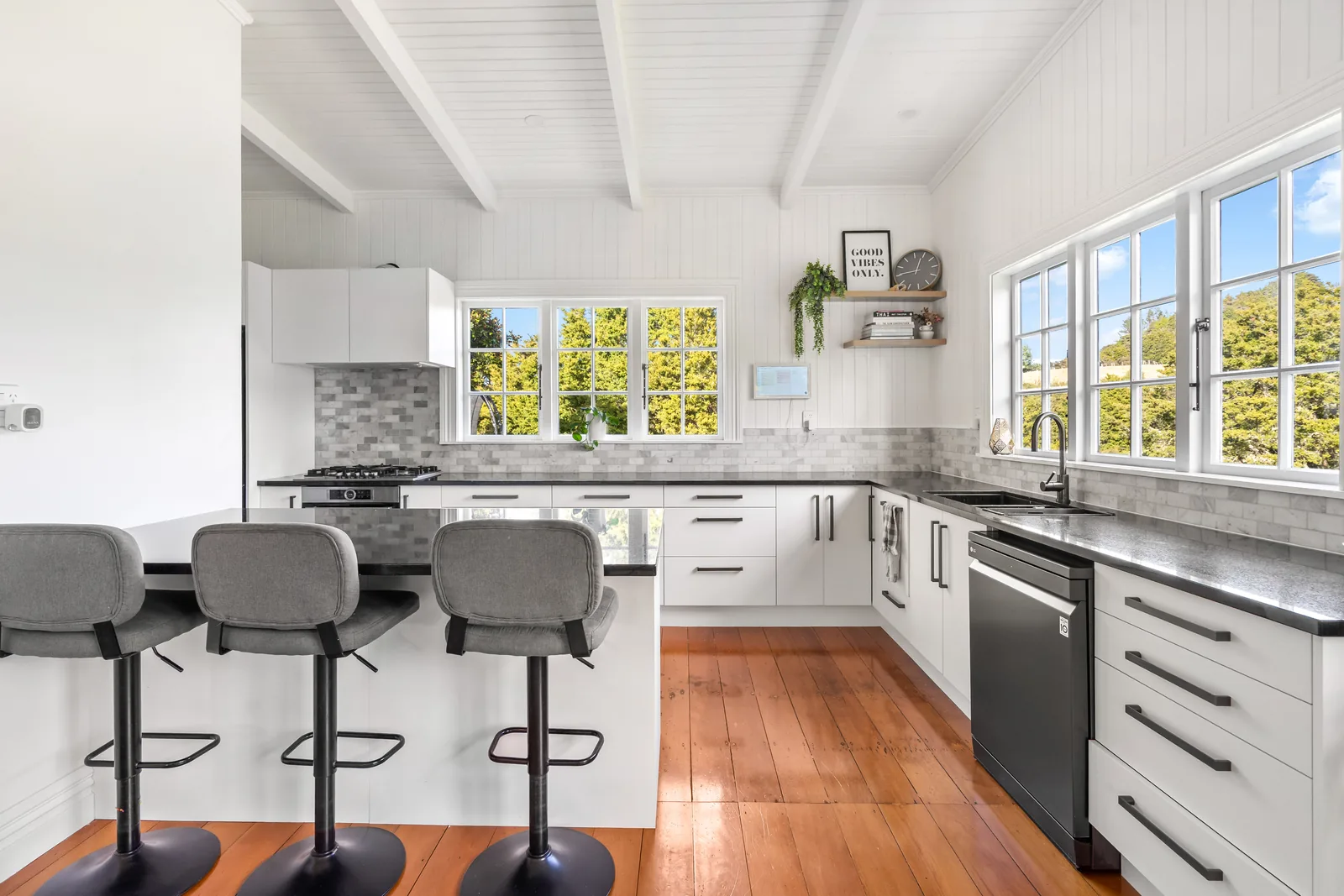 Finished white kitchen with dark worktops and timber flooring
